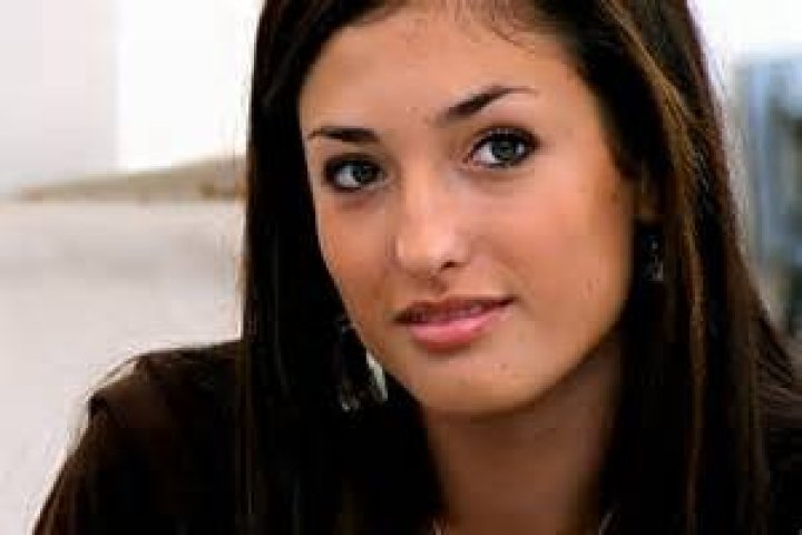 Lexie Contursi posing while wearing gold necklace