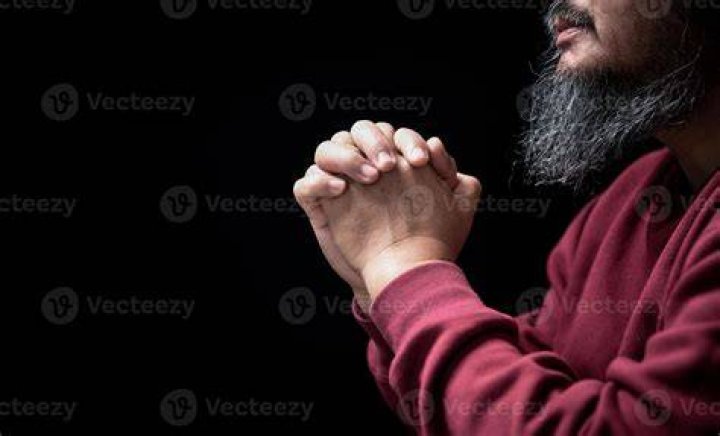 Man with folded hands praying after reading the Bible Man with folded hands praying after reading the Bible