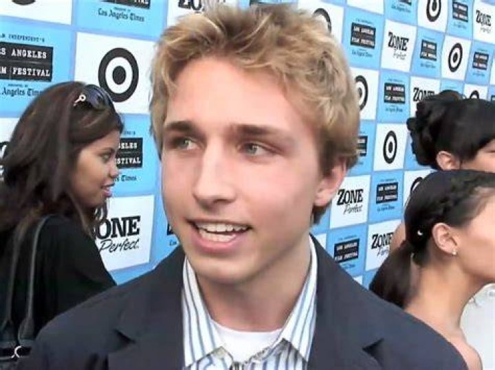Shayne Topp, a white man with a beanie wearing a white shirt and Courtney Miller, a white woman with blonde hair and wearing a white outfit.