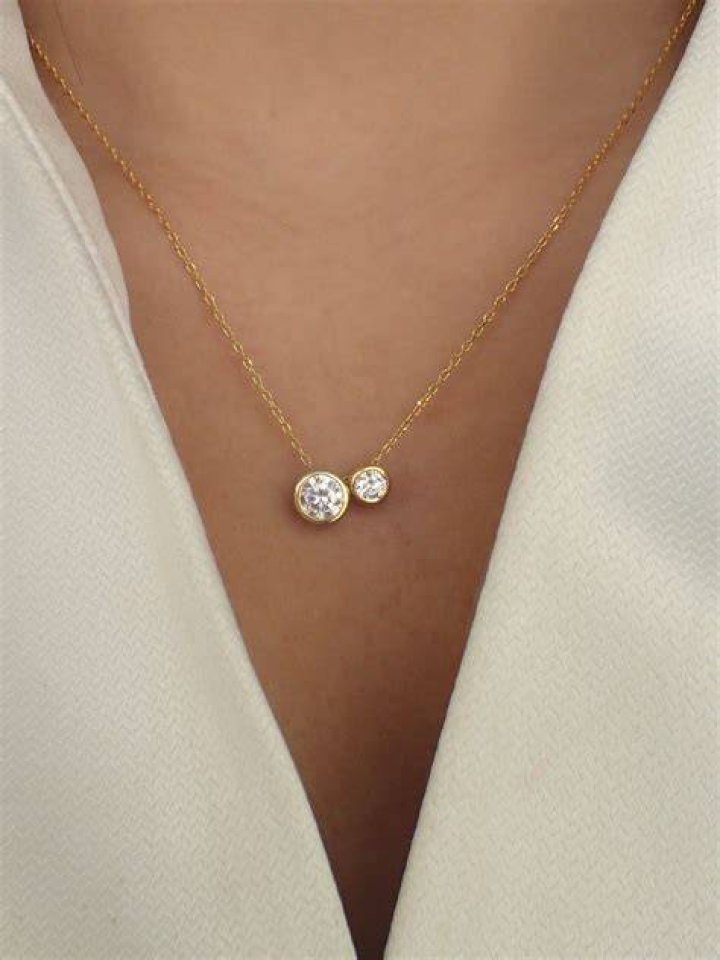 Two solar eclipse pendant necklaces, one silver and one gold