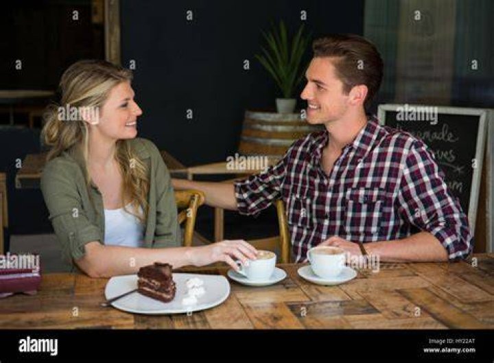 Young couple talking at table with cocktail and beer in public house